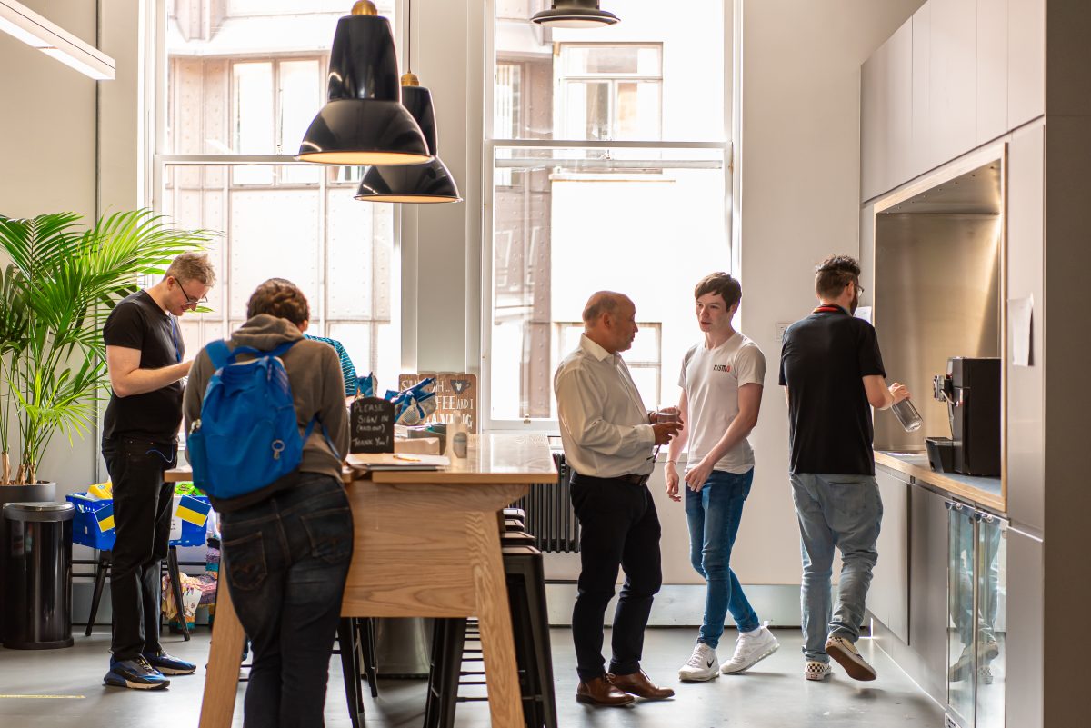 A collection of AutoRek staff gathered around the coffee bar during a workday