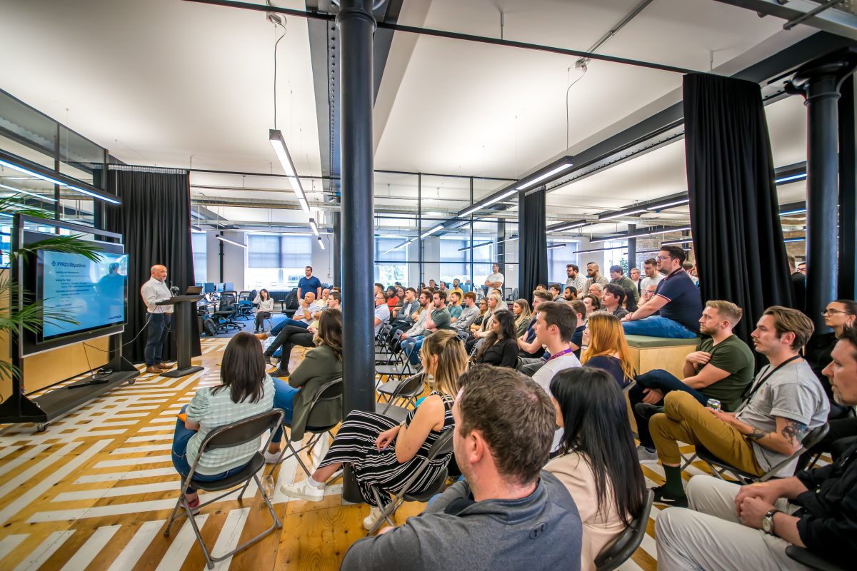 Group photo of all AutoRek staff listening to CEO Gordon McHarg during a company meeting.